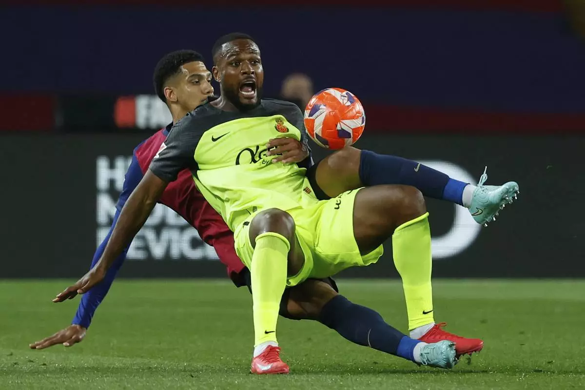 Mallorca's Cyle Larin, foreground, is challenged by Barcelona's Ronald Araujo during a Spanish La Liga soccer match between Barcelona and Mallorca at the Lluis Companys Olympic stadium in Barcelona, Spain, Tuesday, April 22, 2025. (AP Photo/Joan Monfort)