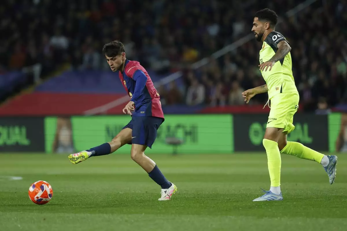 Barcelona's Pedri, right, passes the ball past Mallorca's Omar Mascarell during a Spanish La Liga soccer match between Barcelona and Mallorca at the Lluis Companys Olympic stadium in Barcelona, Spain, Tuesday, April 22, 2025. (AP Photo/Joan Monfort)