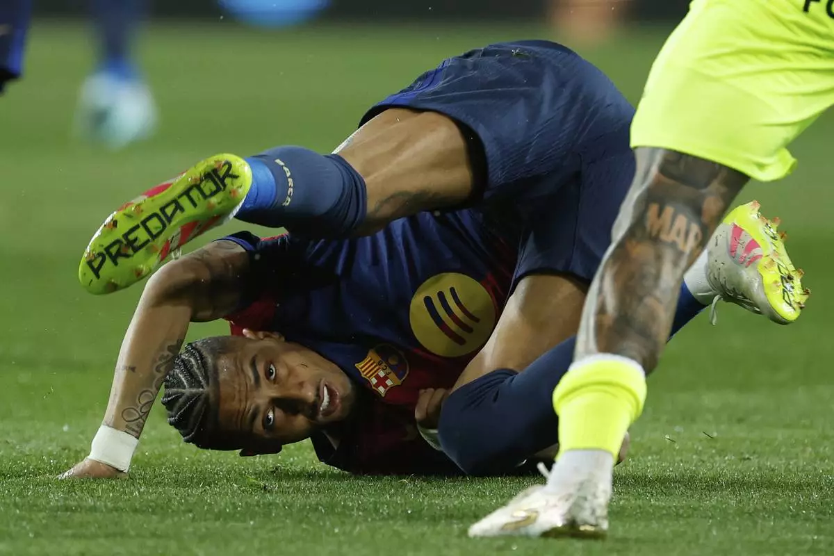 Barcelona's Raphinha falls to the ground after a challenge with Mallorca's Antonio Sanchez during a Spanish La Liga soccer match between Barcelona and Mallorca at the Lluis Companys Olympic stadium in Barcelona, Spain, Tuesday, April 22, 2025. (AP Photo/Joan Monfort)