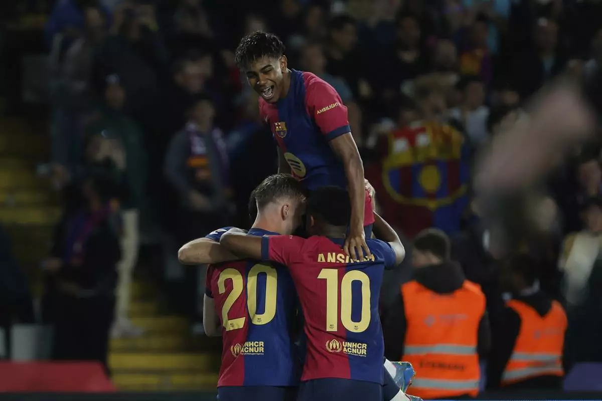 Barcelona's Dani Olmo, left, celebrates with his teammates after scoring his side's opening goal during a Spanish La Liga soccer match between Barcelona and Mallorca at the Lluis Companys Olympic stadium in Barcelona, Spain, Tuesday, April 22, 2025. (AP Photo/Joan Monfort)