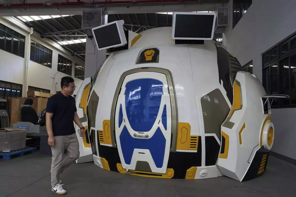A worker past by a virtual reality experience platform built at the factory of Zhuoyuan Tech Co., Ltd in Panyu district of Guangzhou city in southern China's Guangdong province on Wednesday, April 16, 2025. (AP Photo/Ng Han Guan)