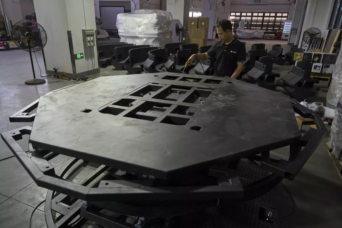 A worker labors on a platform for a virtual reality game machine produced at the factory for Zhuoyuan Tech Co., Ltd in Panyu district of Guangzhou city in southern China's Guangdong province on Wednesday, April 16, 2025. (AP Photo/Ng Han Guan)