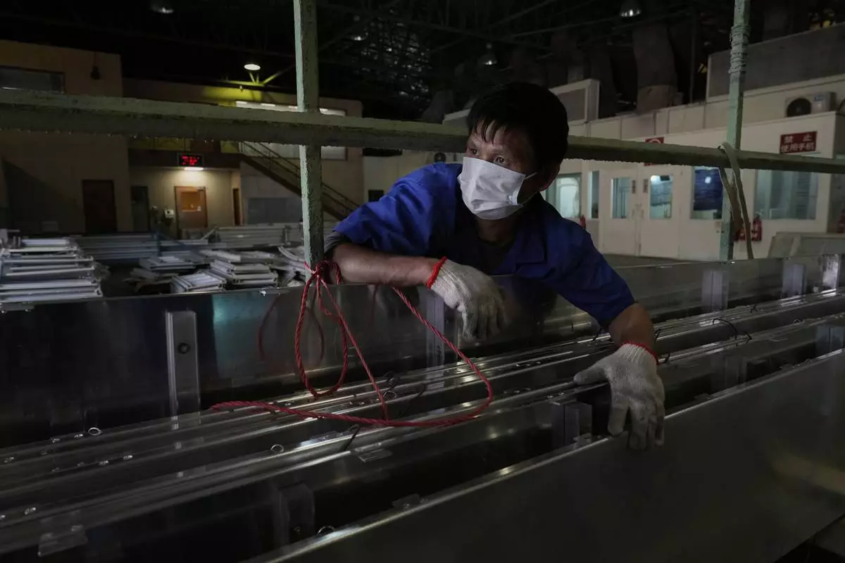 A worker holds together aluminum panels at a factory of Kam Pin Industrial (HK) Ltd, in Dongguan city in southern China's Guangdong province on Thursday, April 17, 2025. (AP Photo/Ng Han Guan)