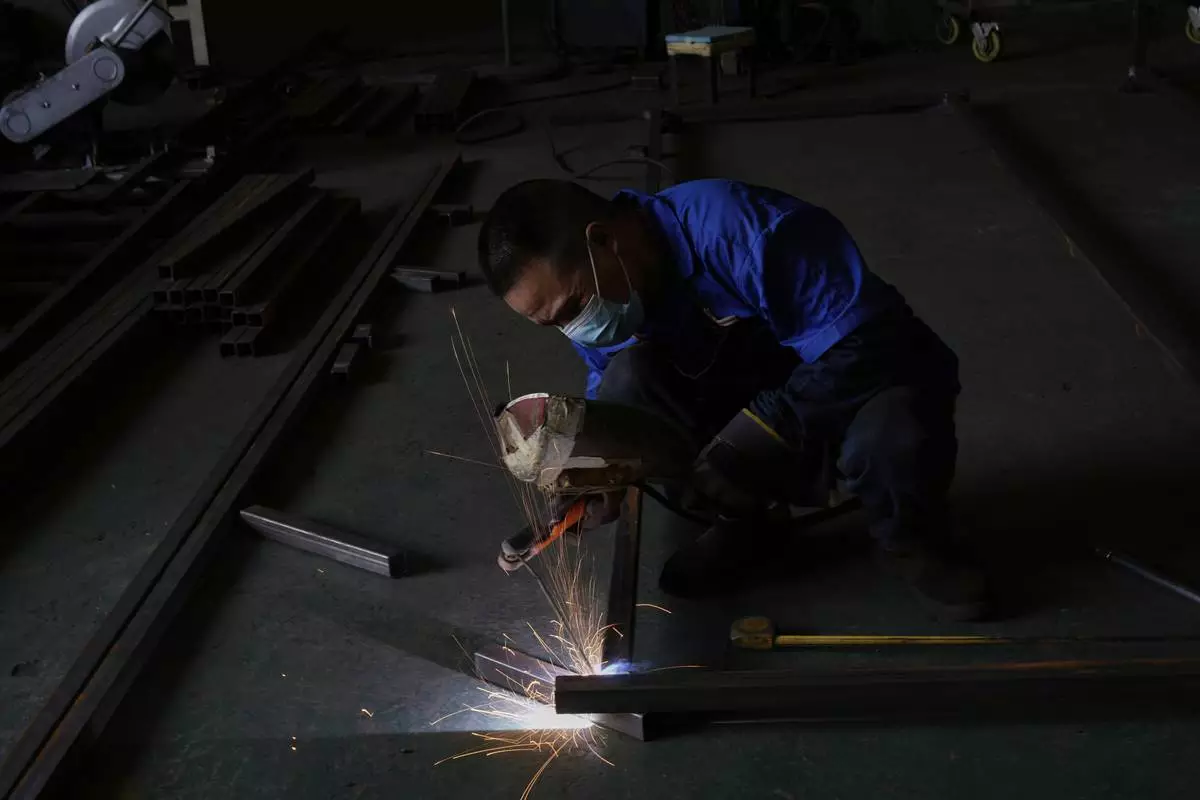 A worker welds together metal parts at the factory of Kam Pin Industrial (HK) Ltd, manufacturer of coated aluminum panels in Dongguan city in southern China's Guangdong province on Thursday, April 17, 2025. (AP Photo/Ng Han Guan)