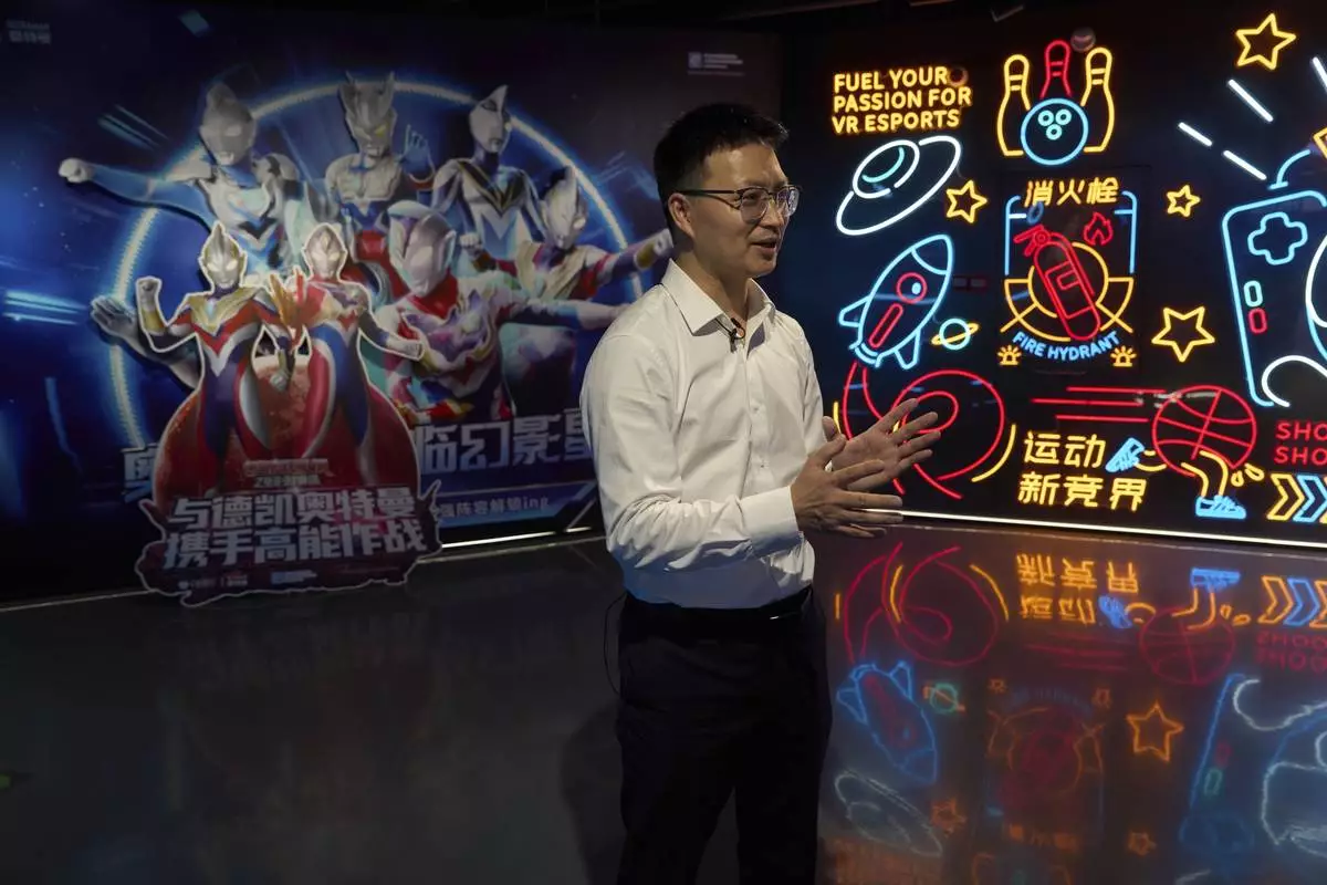 Zou Huajian, overseas sales manager of Zhuoyuan Tech Co., Ltd talks about the Virtual Reality products at the experience center in Panyu district of Guangzhou city in southern China's Guangdong province on Wednesday, April 16, 2025. (AP Photo/Ng Han Guan)
