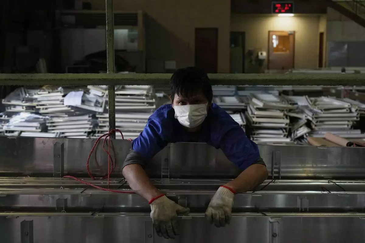 A worker holds together aluminum panels at a factory of Kam Pin Industrial (HK) Ltd, in Dongguan city in southern China's Guangdong province on Thursday, April 17, 2025. (AP Photo/Ng Han Guan)