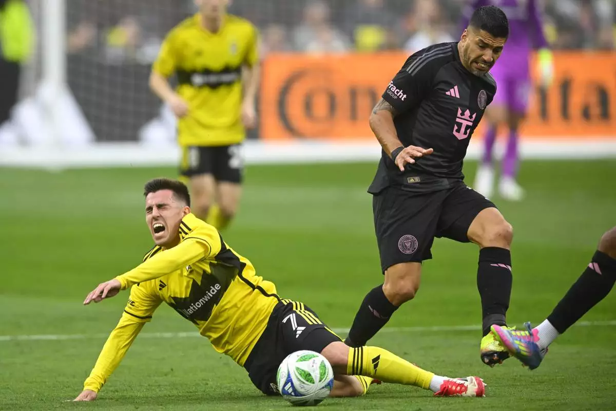 Columbus Crew midfielder Dylan Chambost, left, falls while defended by Inter Miami forward Luis Suarez, right, during the first half of an MLS soccer match Saturday, April 19, 2025, in Cleveland, Ohio. (AP Photo/David Richard)