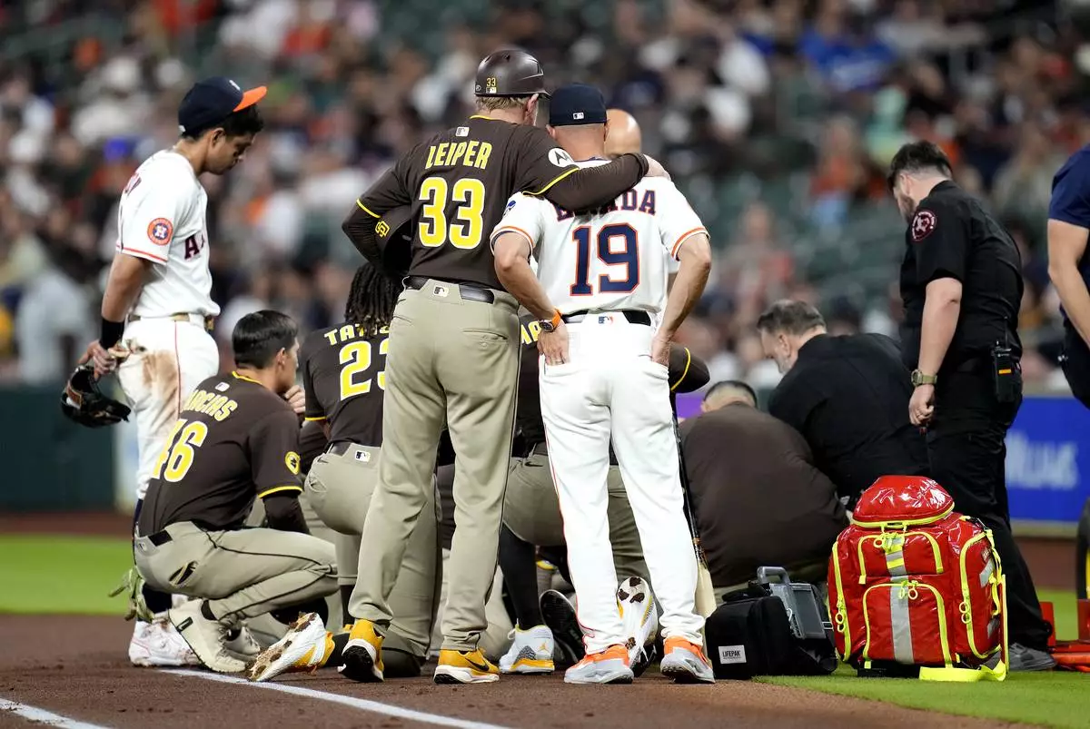 San Diego Padres third base coach Tim Leiper (33) hugs Houston Astros manager Joe Espada (19) after Padres' Luis Arraez lies on the ground after a collision with with Astros second baseman Mauricio Dubon at first base rduring the first inning of a baseball game Sunday, April 20, 2025, in Houston. (AP Photo/Karen Warren)