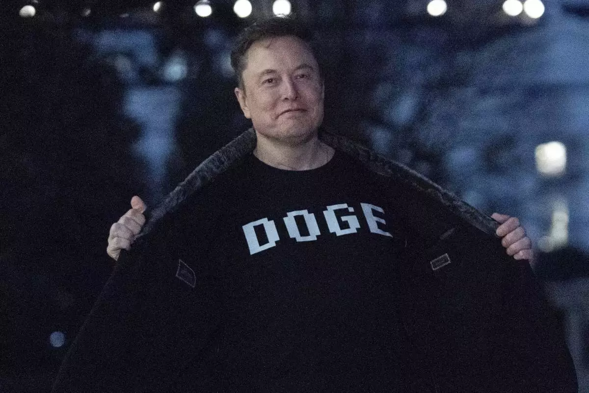 FILE - Elon Musk flashes his T-shirt that reads "DOGE" to the media as he walks on South Lawn of the White House, in Washington, March 9, 2025. (AP Photo/Jose Luis Magana, File)