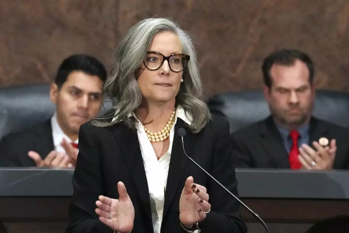 FILE - Arizona Democratic Gov. Katie Hobbs, center, applauds for those affected by the Los Angeles area wildfires as she gives the State of the State address in the House of Representatives at the Capitol with Speaker of the House Rep. Steve Montenegro, R-Litchfield Park, left, and Senate President Warren Petersen, R-Gilbert, flanking the governor on Jan. 13, 2025, in Phoenix. (AP Photo/Ross D. Franklin, File)