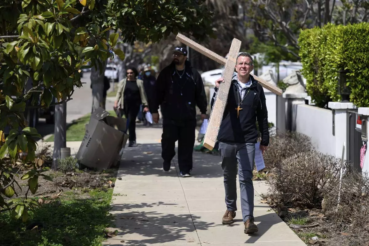 Pastor John Shaver, right, carries a cross during a Cross Walk event by the Community United Methodist Church of the Pacific Palisades, Friday, April 18, 2025, in the Pacific Palisades area of Los Angeles. (AP Photo/William Liang)
