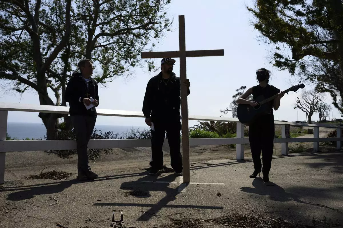 Carli Wright, right, plays a song during a Cross Walk event by the Community United Methodist Church of the Pacific Palisades, Friday, April 18, 2025, in the Pacific Palisades area of Los Angeles. (AP Photo/William Liang)