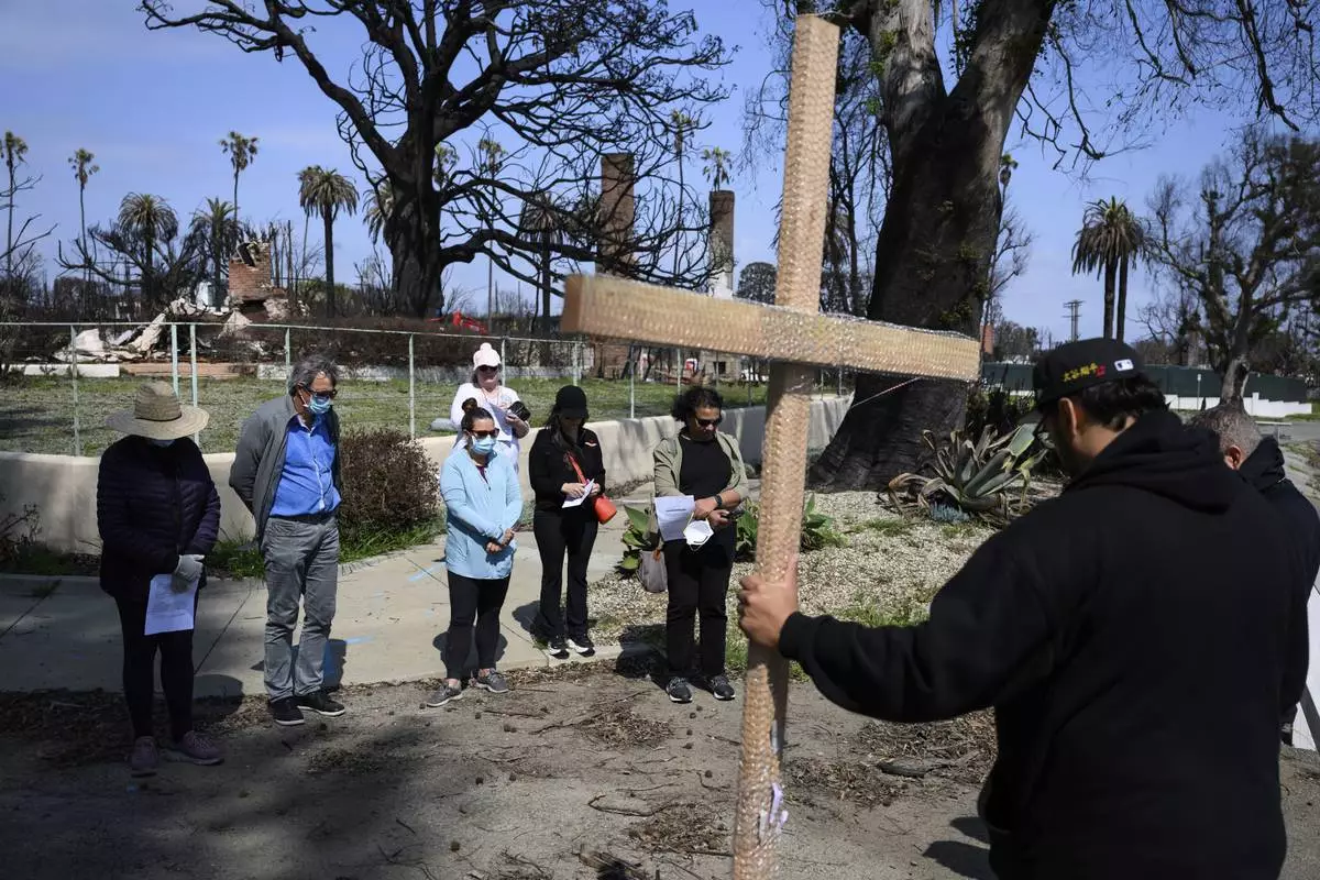 Members of the church listen to a prayer during a Cross Walk event by the Community United Methodist Church of the Pacific Palisades, Friday, April 18, 2025, in the Pacific Palisades area of Los Angeles. (AP Photo/William Liang)
