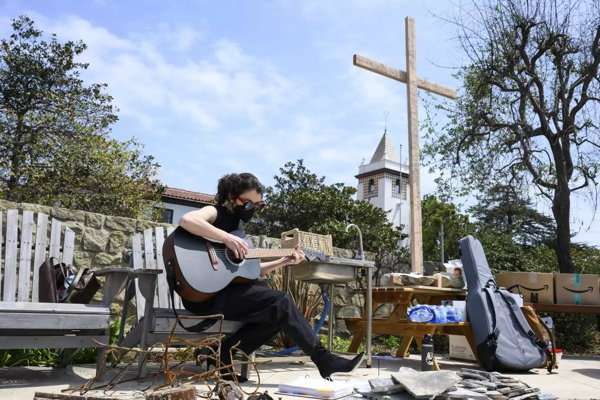 Carli Wright plays music during a Cross Walk event by the Community United Methodist Church of the Pacific Palisades, Friday, April 18, 2025, in the Pacific Palisades area of Los Angeles. (AP Photo/William Liang)