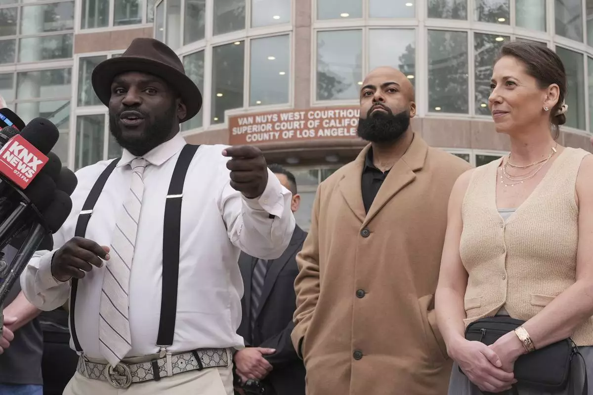 Anerae Brown, left, speaks to the media next to other supporters of Erik and Lyle Menendez, who were sentenced in 1996 to life in prison without the possibility of parole for fatally shooting their parents, after a resentencing hearing in their case, Thursday, April 17, 2025, in Los Angeles. (AP Photo/Damian Dovarganes)