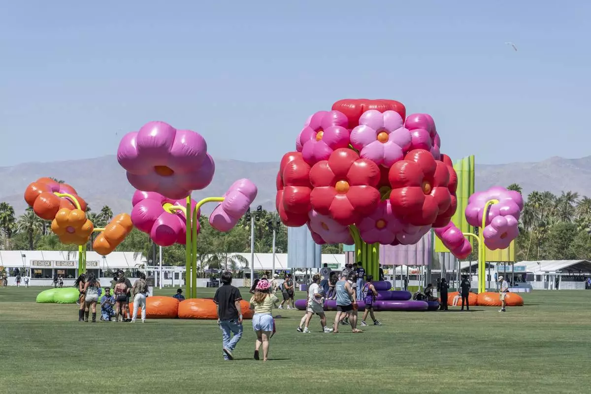 Festivalgoers are seen around the art installation Uchronia / Le Grand Bouquet during the first weekend of the Coachella Valley Music and Arts Festival at the Empire Polo Club on Friday, April 11, 2025, in Indio, Calif. (Photo by Amy Harris/Invision/AP)
