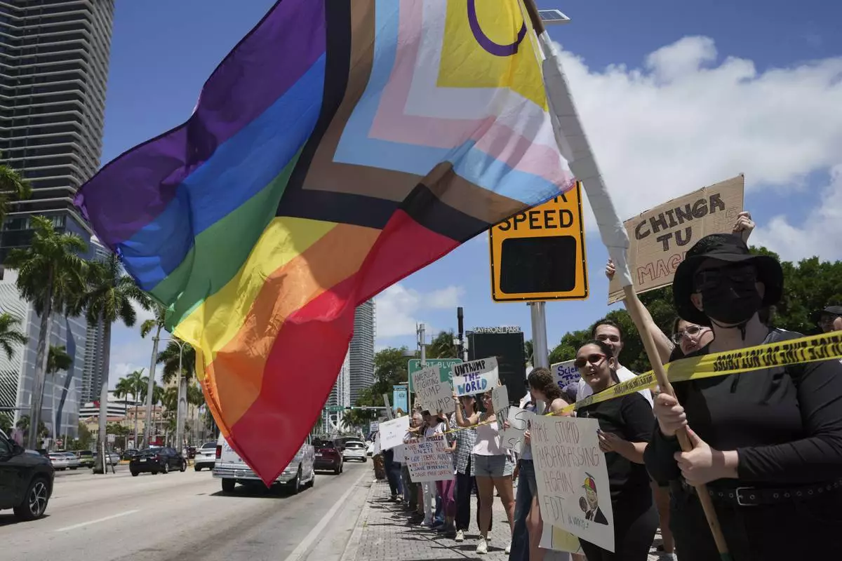 A person waves a rainbow flag during a protest against the Trump administration, Saturday, April 19, 2025, in Miami. (AP Photo/Lynne Sladky)