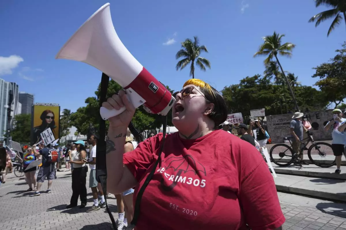 A person who gave their name as "Mistress Mei" chants slogans during a protest against the Trump administration, Saturday, April 19, 2025, in Miami. (AP Photo/Lynne Sladky)