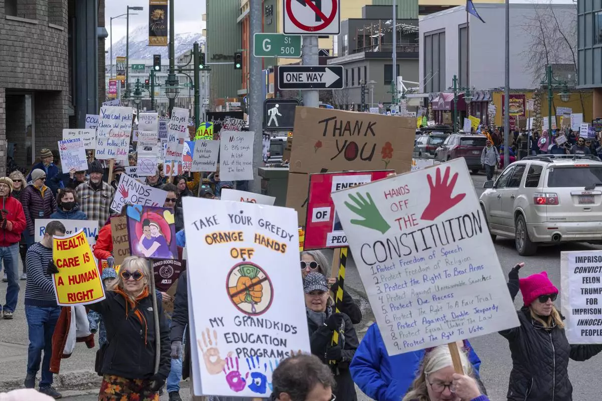 People walk through downtown Anchorage, Alaska, to protest against President Trump and his policies on Saturday, April 19, 2025. (Loren Holmes/Anchorage Daily News via AP)