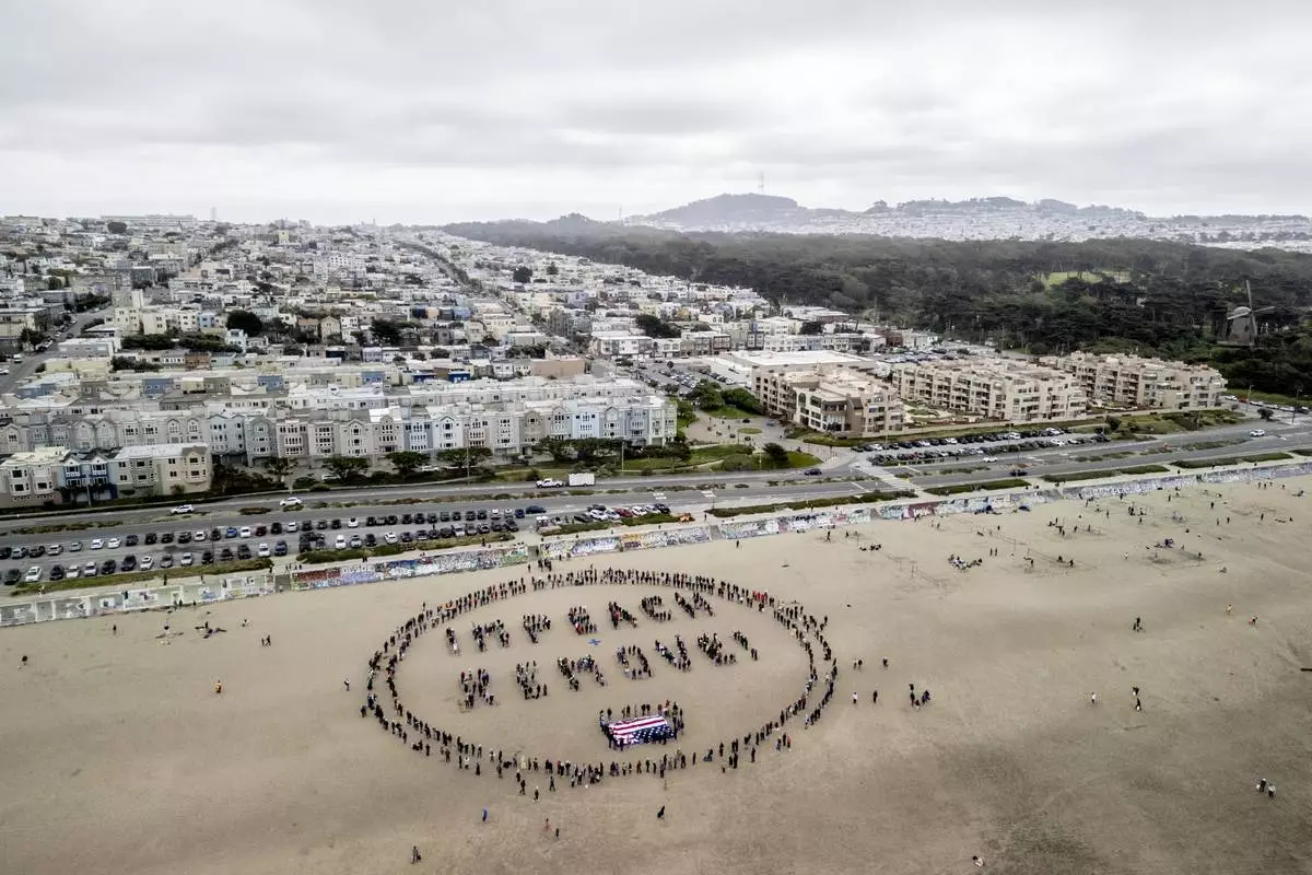 Protesters form a "Impeach & Remove" human banner on Ocean Beach during a protest against U.S. President Donald Trump, in San Francisco, Saturday, April 19, 2025. (Stephen Lam/San Francisco Chronicle via AP)
