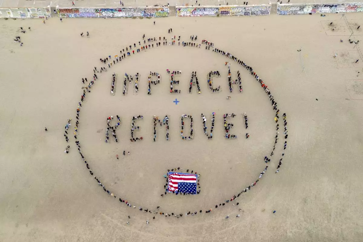 Protesters form a "Impeach & Remove" human banner on Ocean Beach during a protest against U.S. President Donald Trump, in San Francisco, Saturday, April 19, 2025. (Stephen Lam/San Francisco Chronicle via AP)