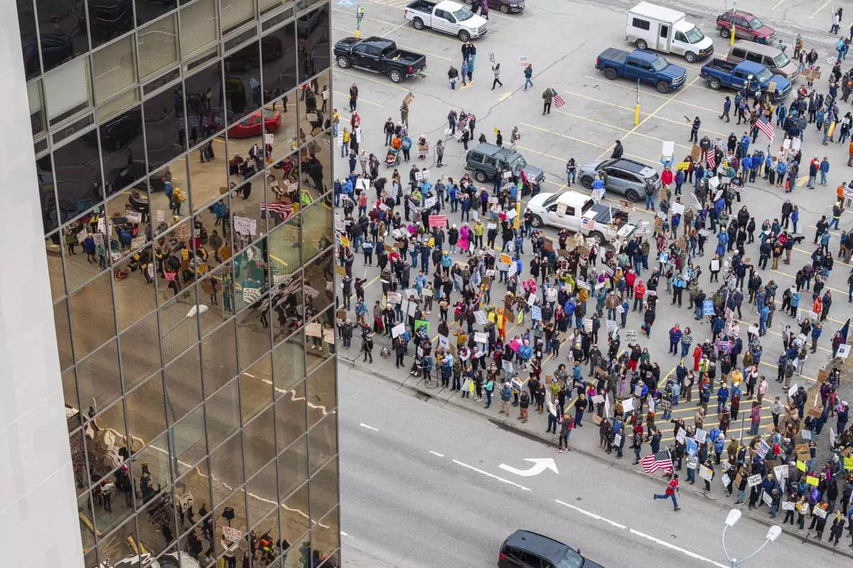 People gather outside the offices of Sen. Lisa Murkowski and Dan Sullivan during a protest against President Trump and his policies on Saturday, April 19, 2025 in Anchorage, Alaska. (Loren Holmes/Anchorage Daily News via AP)