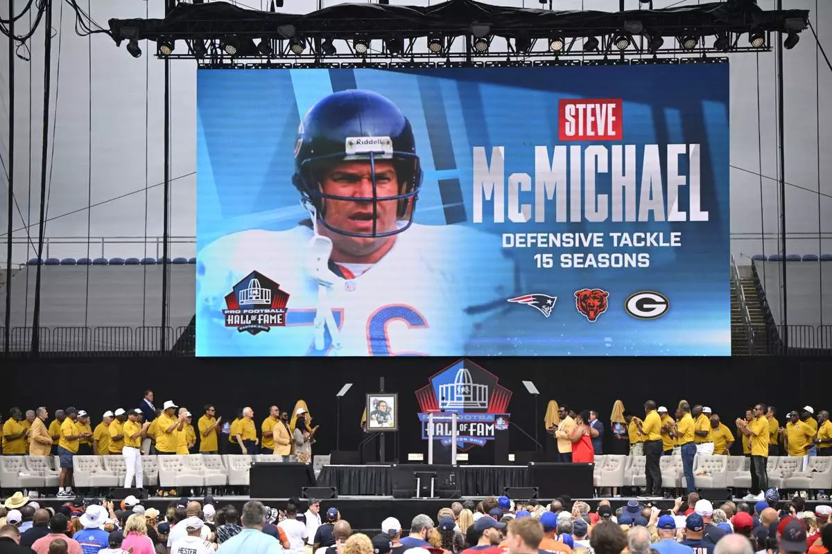 FILE - A video board displays an image of former NFL player Steve McMichael during his induction into the Pro Football Hall of Fame, in Canton, Ohio, Saturday, Aug. 3, 2024. (AP Photo/David Richard,File)