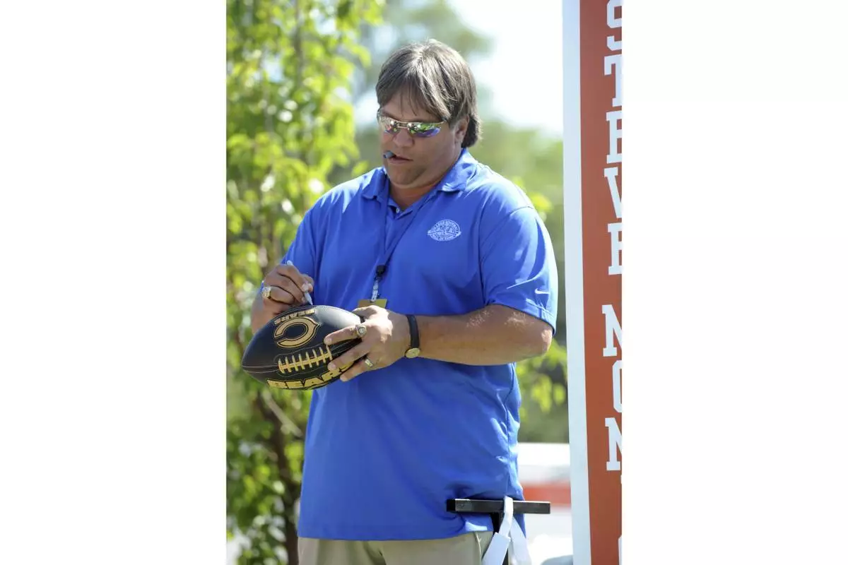 FILE - Former NFL player Steve McMichael, who played defensive tackle at the Univ. of Texas, autographs a football as he stands on the float at the parade during the Hall Enshrinement Festival, Saturday July 17, 2010, in South Bend, Ind. (AP Photo/Joe Raymond, File)