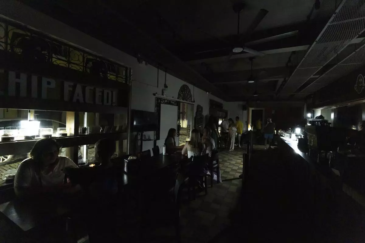 Customers sit inside a restaurant lit by battery-powered lanterns during an island-wide power outage, in Old San Juan, Puerto Rico, Wednesday, April 16, 2025. (AP Photo/Alejandro Granadillo)