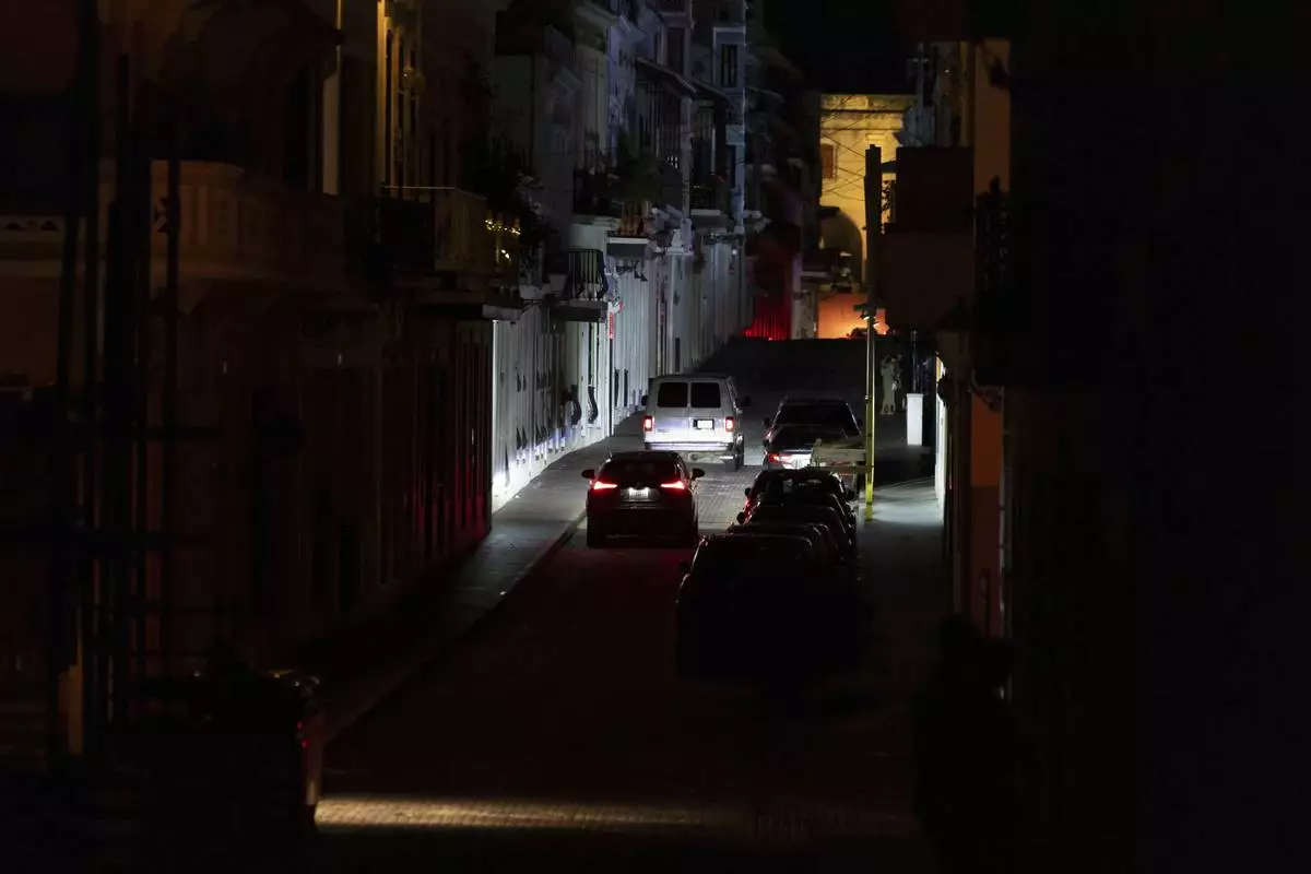 Vehicles navigate a dark street in Old San Juan, Puerto Rico, during an island-wide blackout, Wednesday, April 16, 2025. (AP Photo/Alejandro Granadillo)
