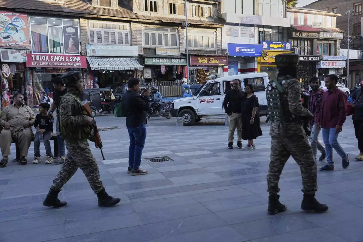 Indian paramilitary soldiers patrol as tourists take pictures at a busy market in Srinagar, Indian controlled Kashmir, Tuesday, April 29, 2025. (AP Photo/Mukhtar Khan)
