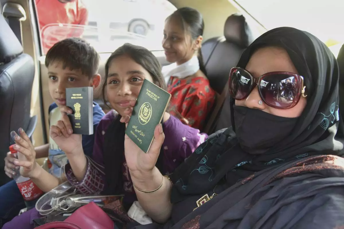Pakistani national Khalida Hanif, right, and her Indian children display their passports on their return from Pakistan at the Attari-Wagah border between India and Pakistan, near Amritsar, India, Tuesday, April 29, 2025. (AP Photo/Prabhjot Gill)