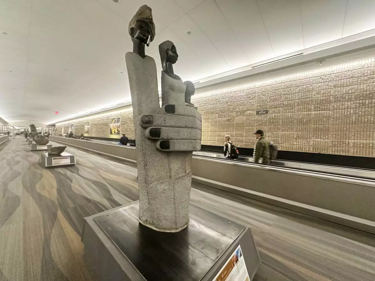 People walk by a Zimbabwean sculpture piece at Hartsfield-Jackson Atlanta International Airport, Friday, Feb. 28, 2025, in Atlanta. (AP Photo/Ravi Nessman)