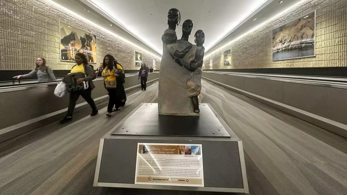People walk by a Zimbabwean sculpture piece at Hartsfield-Jackson Atlanta International Airport, Friday, Feb. 28, 2025, in Atlanta. (AP Photo/Ravi Nessman)