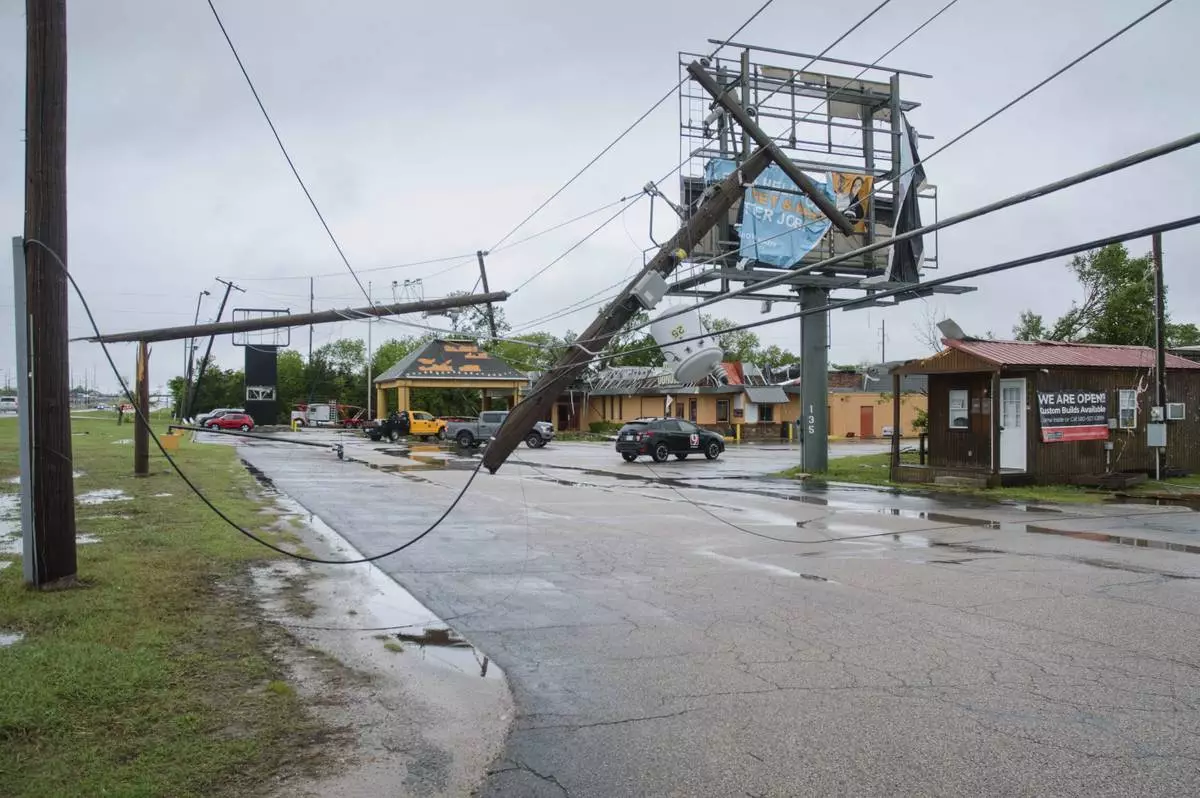 Broken power poles and power lines dangle across the parking lot of Quality Inn in Ada, Okla., after severe weather passed the area Sunday, April 20, 2025. (Richard R. Barron/The ADA News via AP)
