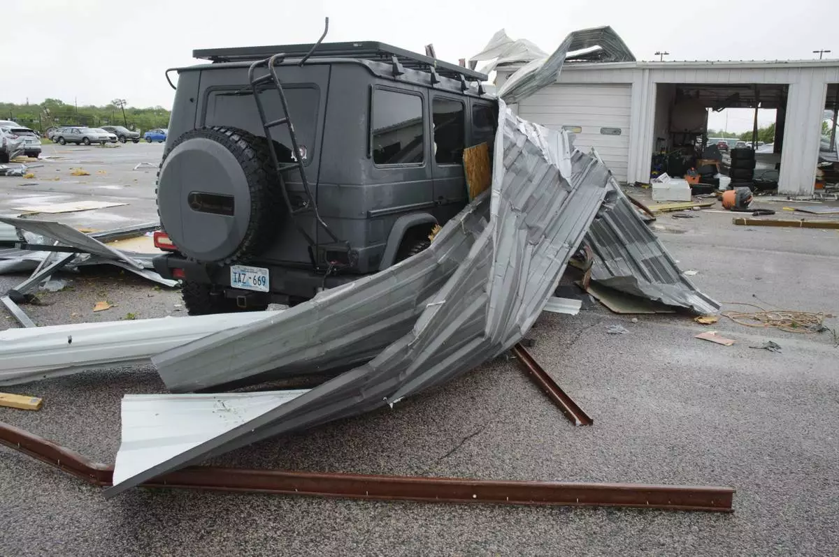 Sheet metal roofing hangs on a damaged car at a local car dealership in Ada, Okla., after severe weather passed the area Sunday, April 20, 2025. (Richard R. Barron/The ADA News via AP)