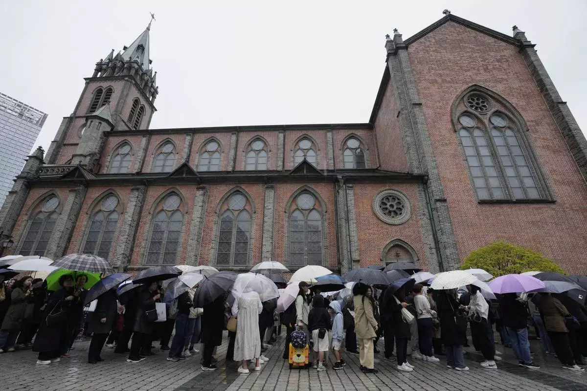 People wait in line to enter Myeongdong Cathedral to pay tribute for the late Pope Francis in Seoul, South Korea, Tuesday, April 22, 2025. (AP Photo/Ahn Young-joon)