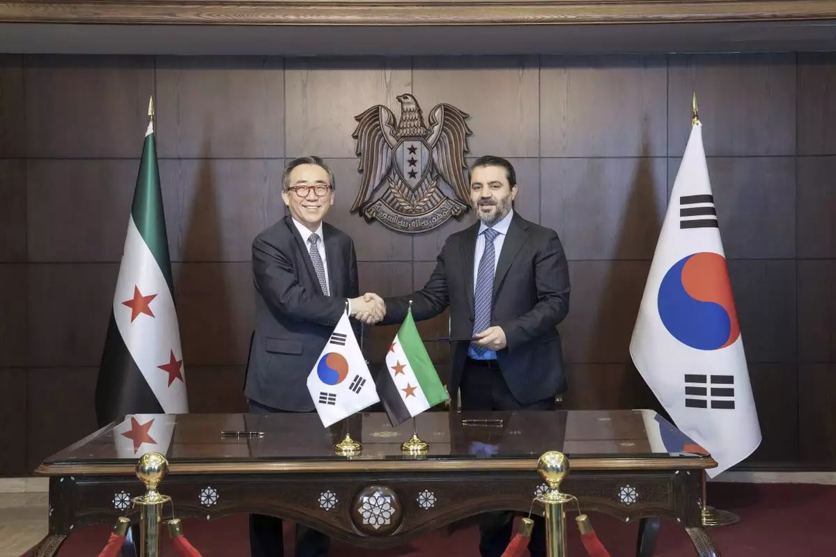In this photo provided by South Korea Foreign Ministry, South Korean Foreign Minister Cho Tae-yul, left, shakes hands with Syrian Foreign Minister Asaad al-Shaibani after signing a joint statement on the establishment of diplomatic ties between the countries in Damascus, Syria, Thursday, April 10, 2025. (South Korea Foreign Ministry via AP)