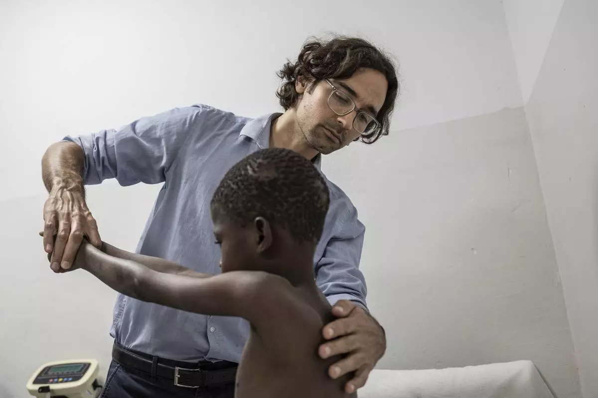 Rare disease researcher Pedro Rodriguez, left, examines Ibrahima Ndiaye, 8, in Dakar, Senegal, Friday, Jan. 10, 2025. (AP Photo/Annika Hammerschlag)