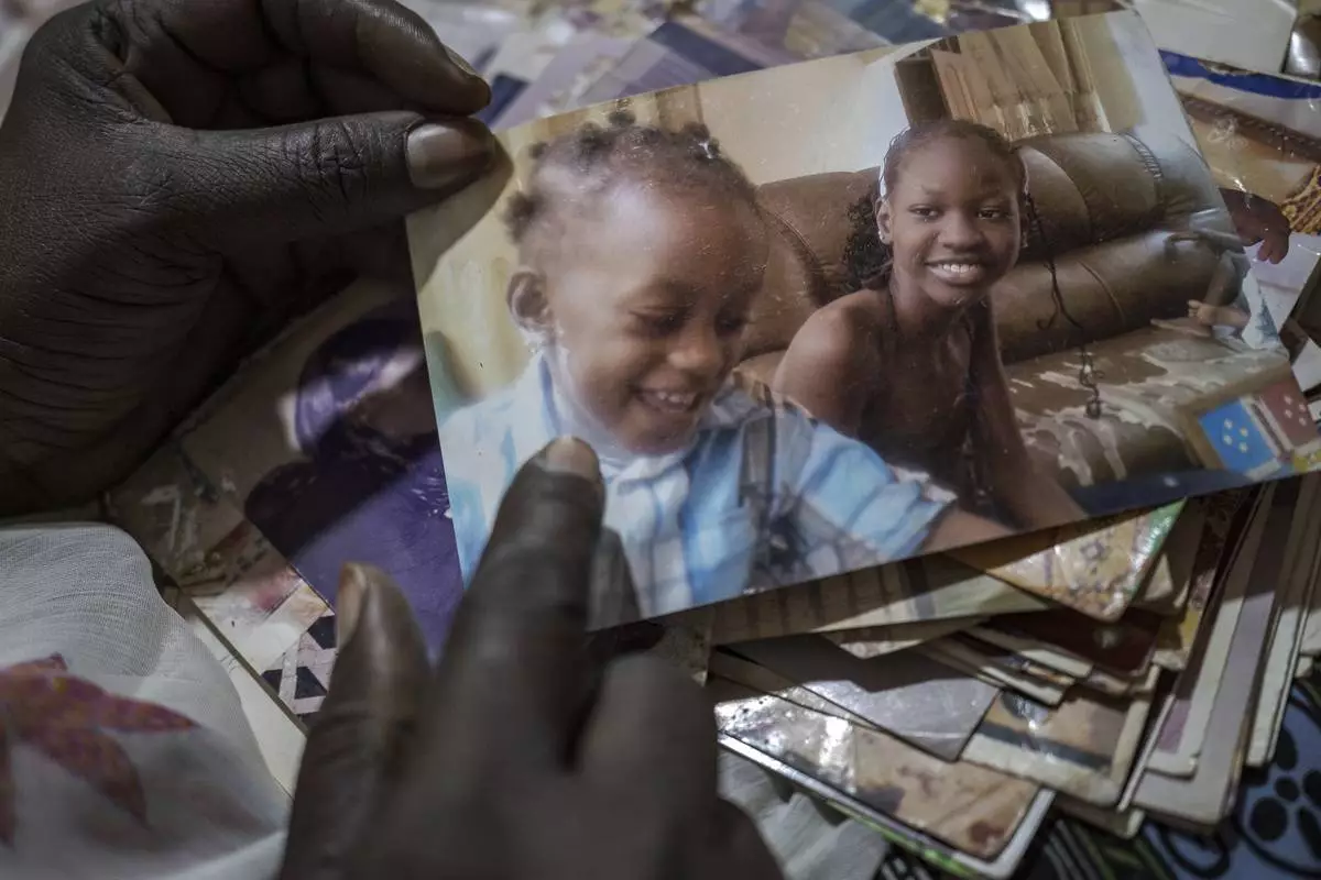Ndeye Lam looks at photos of her deceased daughter Mariama who died at age 13 of a rare genetic disease, in Dakar, Senegal, Saturday, Jan. 11, 2025. (AP Photo/Annika Hammerschlag)