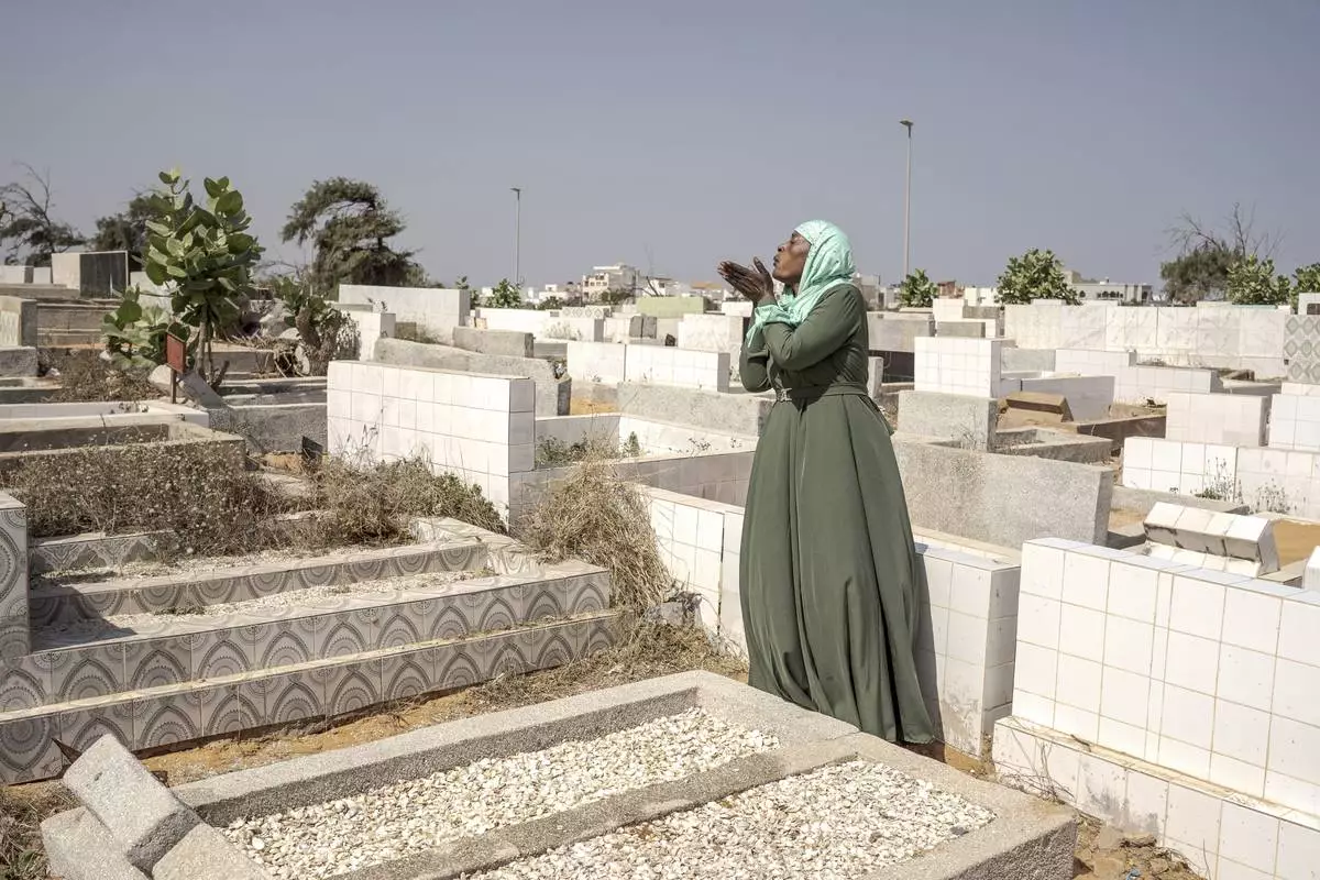 Ndeye Lam sends a prayer at the foot of her daughter Mariama's grave in Dakar, Senegal, Saturday, Jan. 11, 2025. (AP Photo/Annika Hammerschlag)