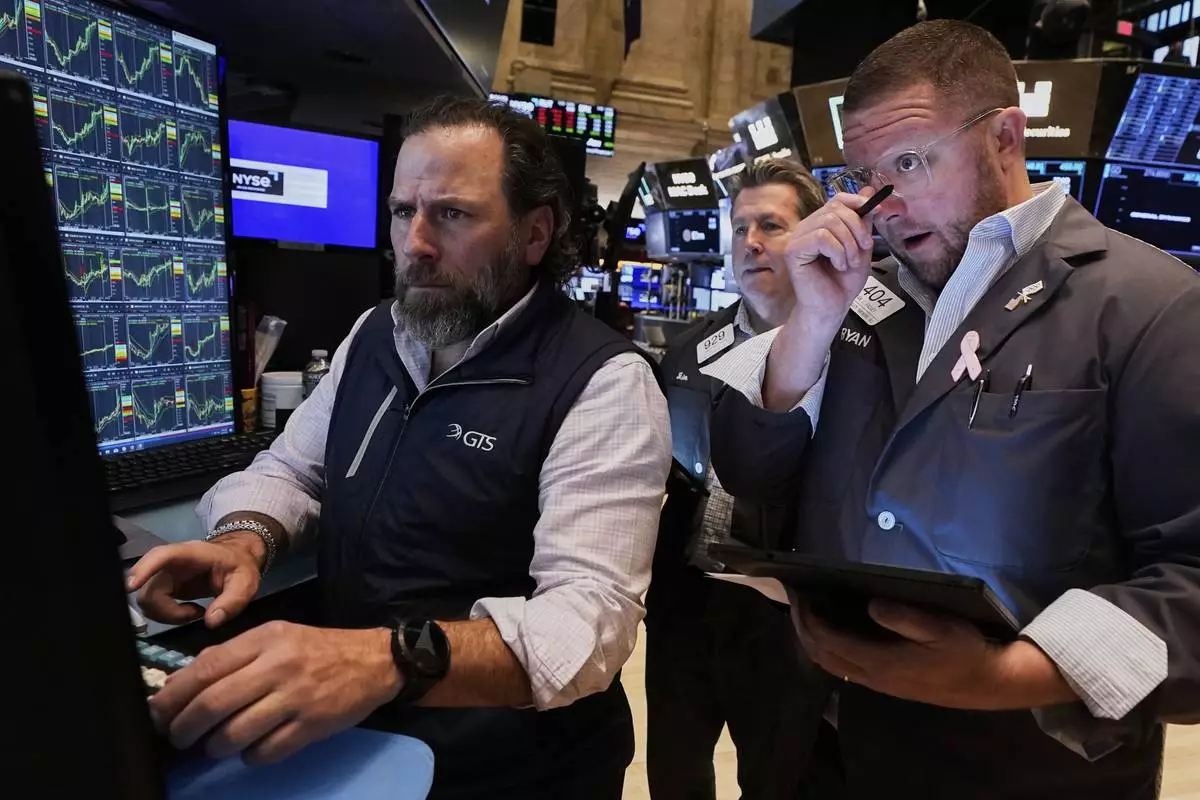 Specialist Michel Pistillo, left, works with traders James Matthews, center, and Ryan Falvey on the floor of the New York Stock Exchange, Wednesday, April 23, 2025. (AP Photo/Richard Drew)