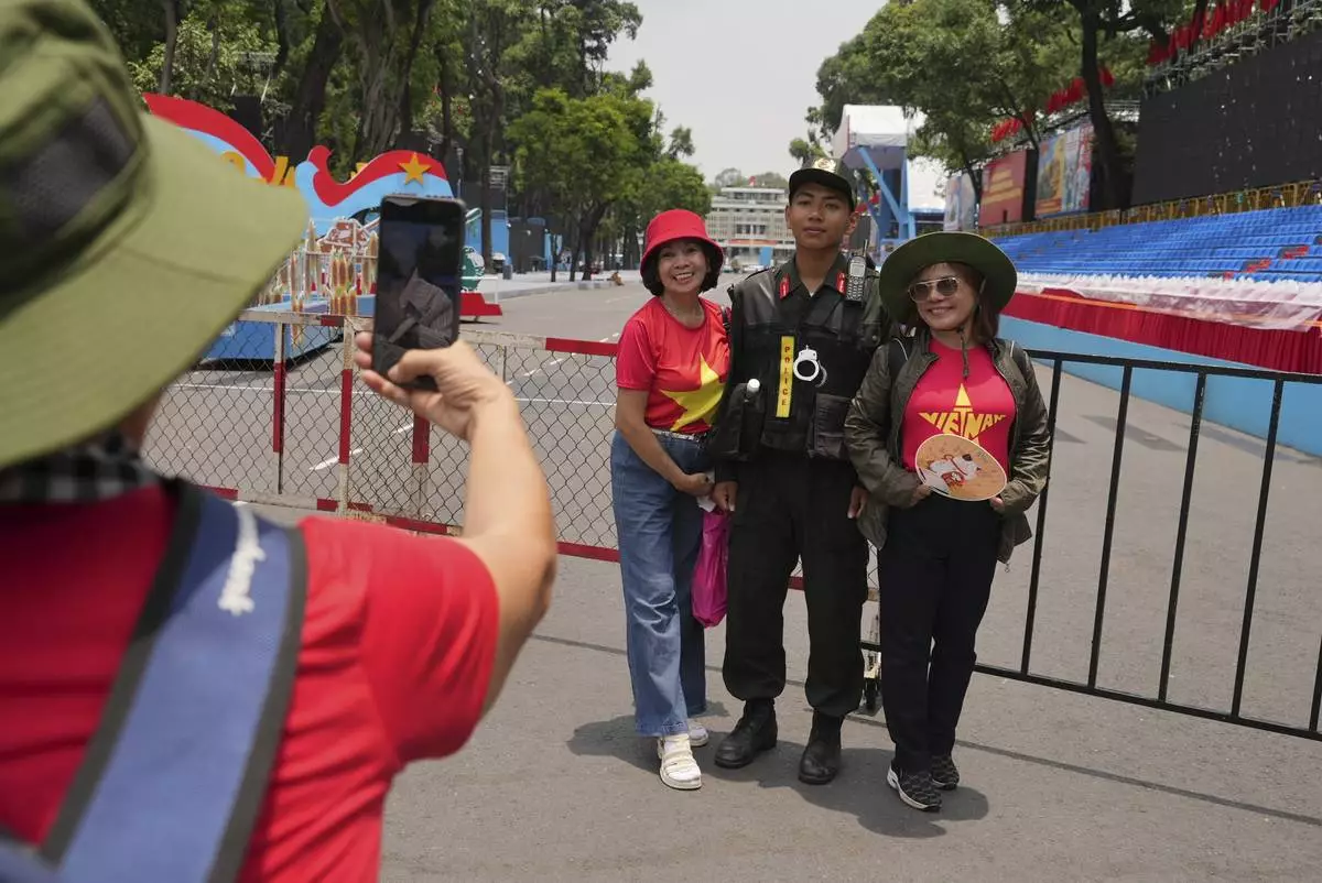 People take photos with a security officer at the venue for a parade to be held on April 30 to celebrate the 50th anniversary of the end of the Vietnam War in Ho Chi Minh City, Vietnam Tuesday, April 29, 2025. (AP Photo/Hau Dinh)
