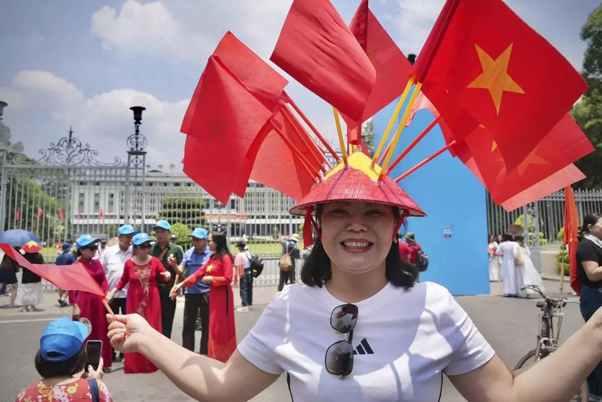 //A woman wears a conical hat decorated with Vietnamese flags to celebrate the 50th anniversary of the end of the Vietnam War in front of the Independence Palace in Ho Chi Minh City, Vietnam Tuesday, April 29, 2025. (AP Photo/Hau Dinh)