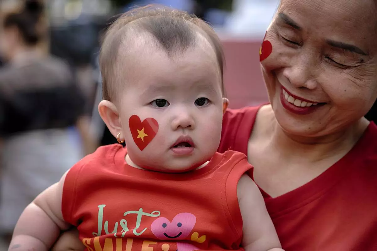 A baby girl sporting a heart with a yellow star takes in the festivities for the national celebrations of the 50th Anniversary of reunification and the end of the Vietnamese War, in Ho Chi Minh City, Vietnam, on Tuesday, April 29, 2025. (AP Photo/Richard Vogel)