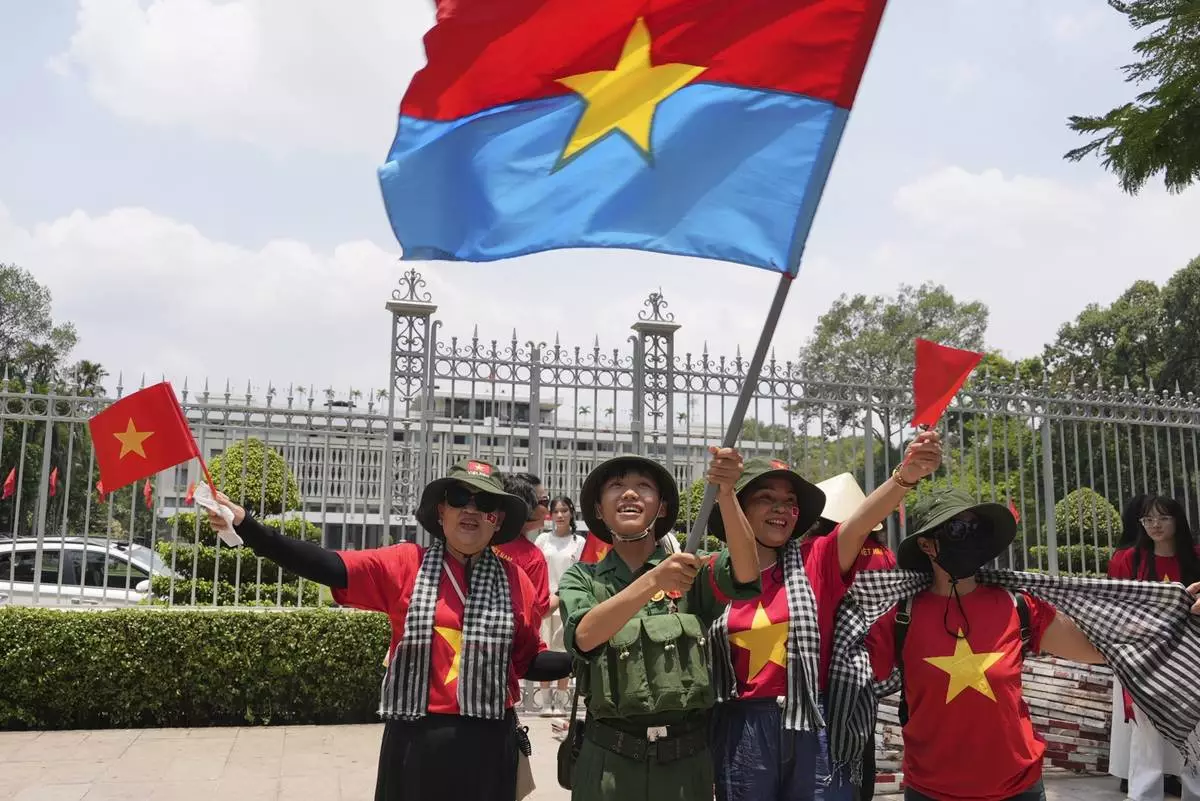 People wave Vietnamese flags and the flag of the former National Liberation Front (NLF) to celebrate the 50th anniversary of the end of the Vietnam War in front of the Independence Palace in Ho Chi Minh City, Vietnam Tuesday, April 29, 2025. (AP Photo/Hau Dinh)