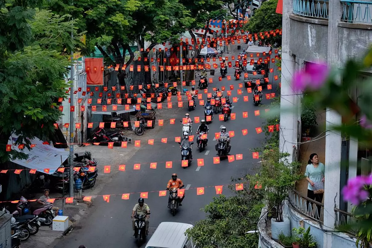 Motorbikes drive along a street under Vietnamese flags in the Cholon district of Ho Chi Minh City, Vietnam, on Tuesday, April 29, 2025 ahead of the 50th anniversary of the end of the Vietnamese War. (AP Photo/Richard Vogel)
