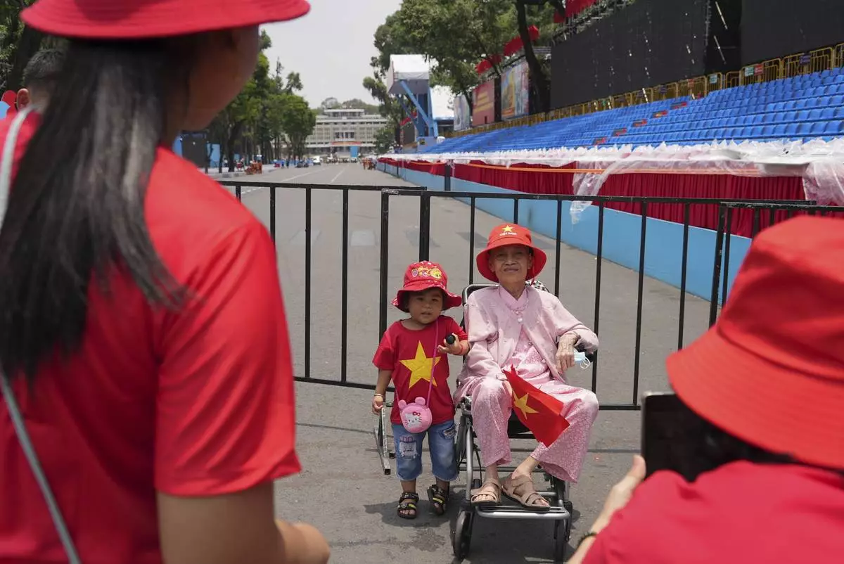A woman and her grandchild take photos at the venue for a parade to be held on April 30 to celebrate the 50th anniversary of the end of the Vietnam War in Ho Chi Minh City, Vietnam Tuesday, April 29, 2025. (AP Photo/Hau Dinh)