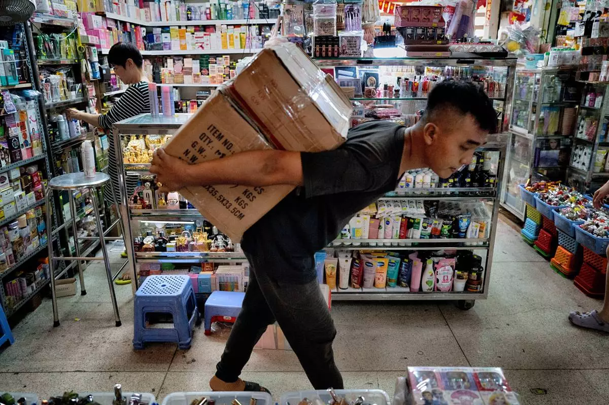 A vendor prepares her shop of various sundry items as a worker carries imported goods into the Cholon market in Ho Chi Minh City, Vietnam, on Tuesday, April 29, 2025 ahead of national celebration of the 50th Anniversary of reunification and the end of the Vietnam War. (AP Photo/Richard Vogel)