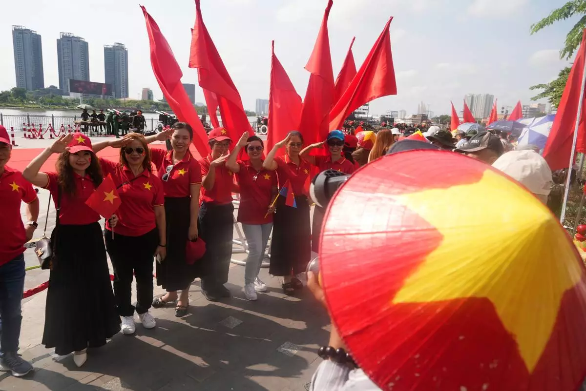 People in Vietnam flag T-shirts pose in front of a line of cannons used for the 50th anniversary of the end of the Vietnam War in Ho Chi Minh City, Vietnam Tueday, April 29, 2025. (AP Photo/Hau Dinh)